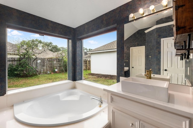 bathroom with lofted ceiling, a bathtub, and vanity