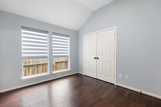 unfurnished bedroom featuring a closet, lofted ceiling, and dark hardwood / wood-style floors