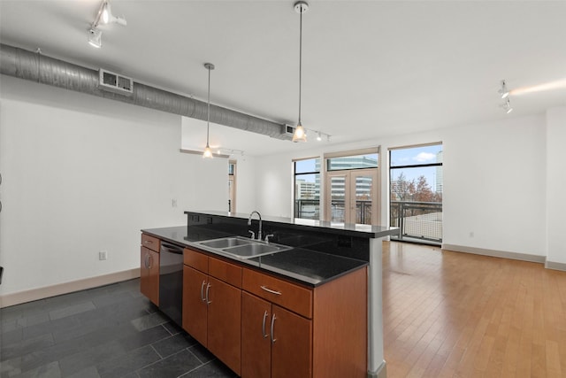 kitchen with sink, stainless steel dishwasher, hanging light fixtures, and an island with sink