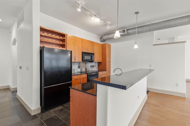 kitchen with kitchen peninsula, pendant lighting, tasteful backsplash, and black appliances