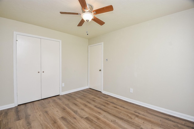 unfurnished bedroom featuring light wood-type flooring, ceiling fan, and a closet