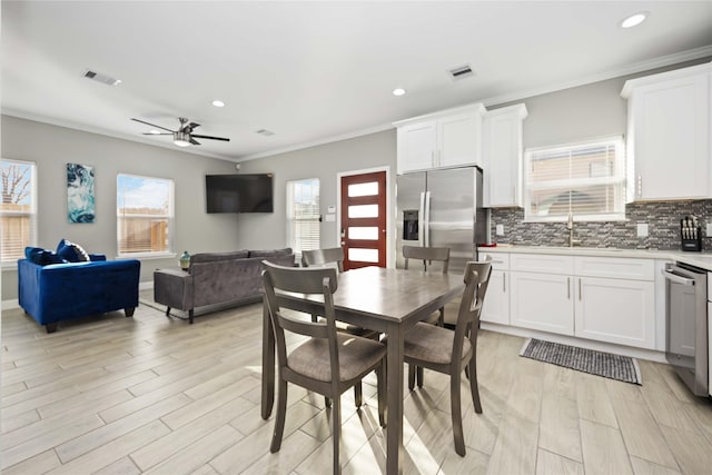 dining room featuring ceiling fan, sink, ornamental molding, and light hardwood / wood-style floors