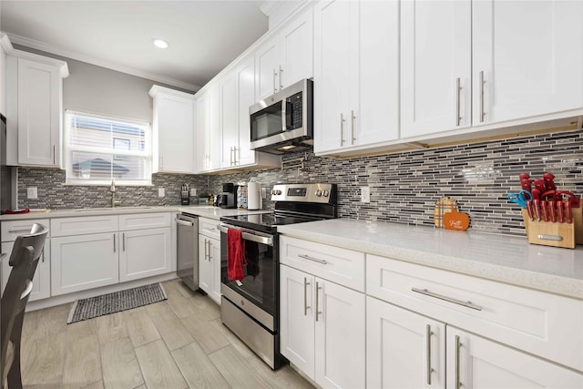 kitchen with tasteful backsplash, sink, light stone countertops, appliances with stainless steel finishes, and white cabinets