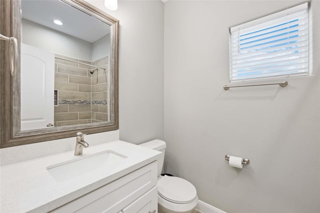 bathroom with toilet, vanity, and a tile shower