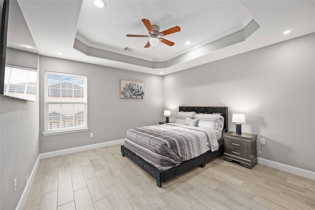 bedroom with ceiling fan, light hardwood / wood-style floors, ornamental molding, and a raised ceiling