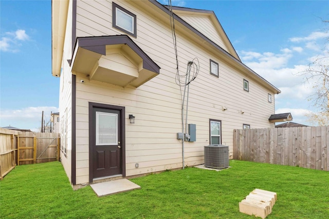 back of house featuring central AC unit and a yard