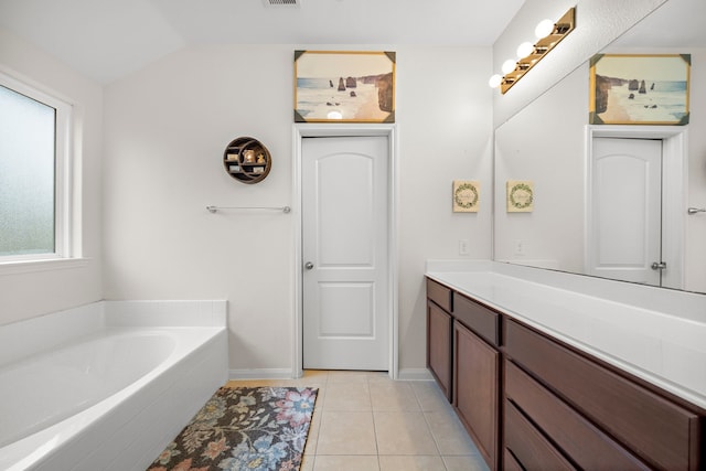 bathroom featuring lofted ceiling, vanity, tile patterned floors, and a washtub