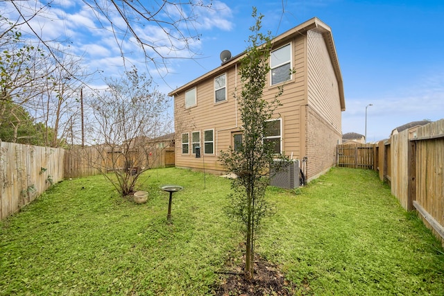 back of property featuring central air condition unit and a yard