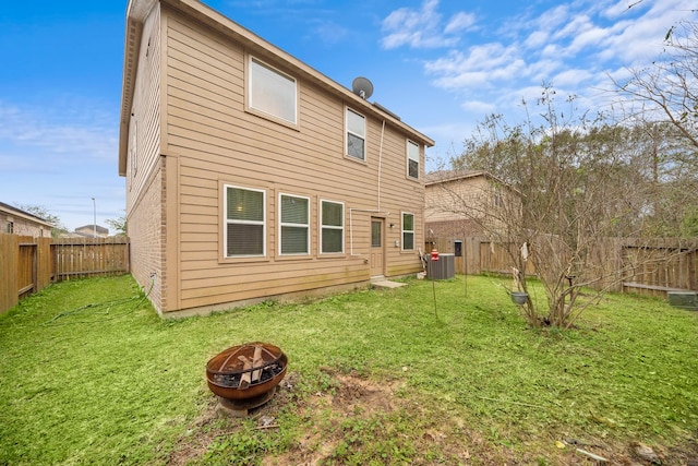 back of house with an outdoor fire pit, a yard, and central AC unit