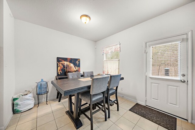 dining area with a textured ceiling, light tile patterned flooring, and plenty of natural light