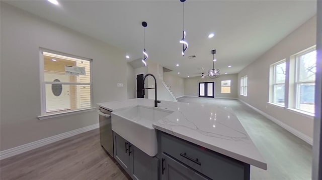 kitchen featuring dishwasher, decorative light fixtures, an island with sink, sink, and gray cabinets