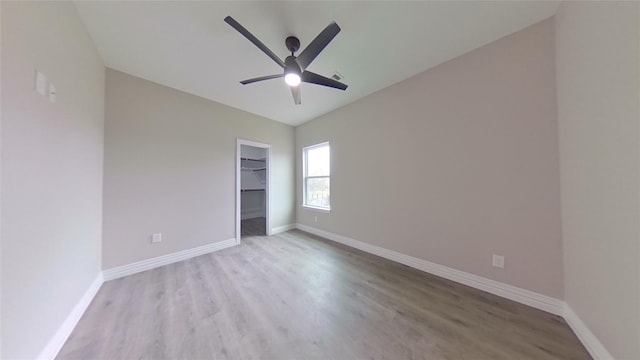 unfurnished bedroom featuring a spacious closet, ceiling fan, a closet, and light hardwood / wood-style floors