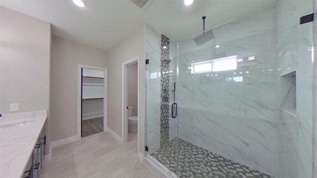 bathroom featuring toilet, a shower with door, and vanity