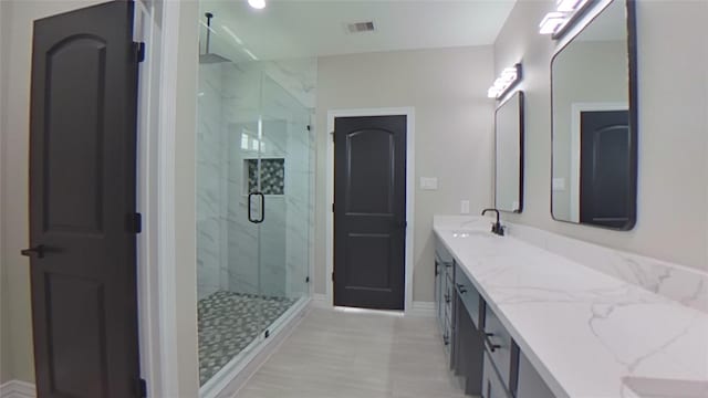 bathroom featuring a shower with door and vanity