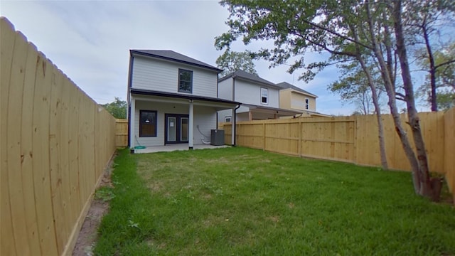 rear view of house featuring cooling unit, a yard, and a patio