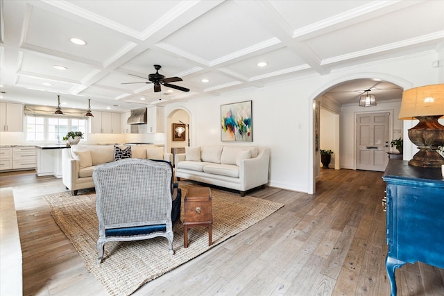 living room featuring hardwood / wood-style floors, beamed ceiling, ornamental molding, ceiling fan, and coffered ceiling