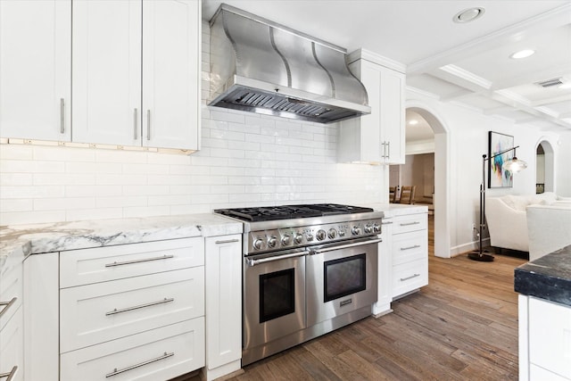 kitchen featuring wall chimney range hood, beamed ceiling, tasteful backsplash, double oven range, and coffered ceiling