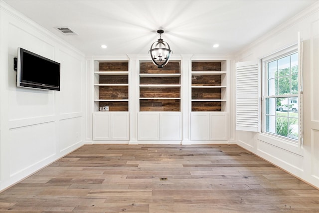 unfurnished dining area with plenty of natural light, built in shelves, and crown molding