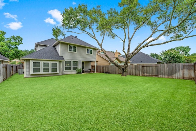 rear view of property featuring a lawn and central air condition unit