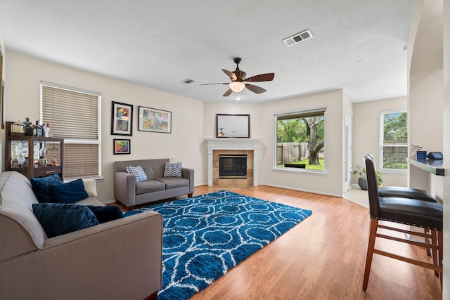 living room featuring ceiling fan, a fireplace, and light hardwood / wood-style flooring