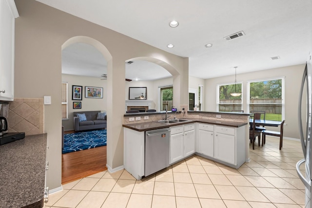 kitchen featuring light tile patterned floors, decorative light fixtures, dishwasher, white cabinets, and sink