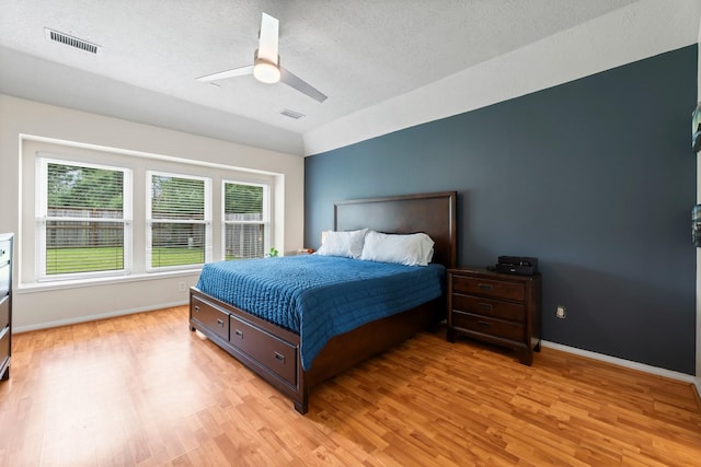 bedroom with ceiling fan, light wood-type flooring, and a textured ceiling