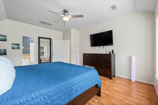 bedroom featuring ceiling fan, vaulted ceiling, ensuite bathroom, and light hardwood / wood-style flooring