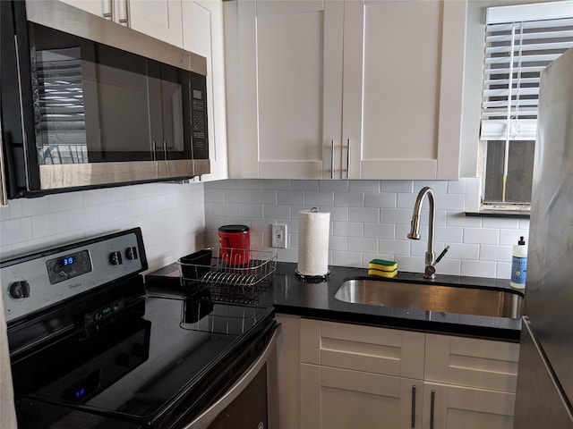 kitchen featuring tasteful backsplash, white cabinets, sink, and stainless steel appliances