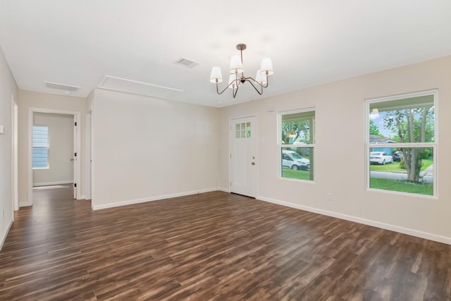 spare room featuring dark wood-type flooring and a chandelier