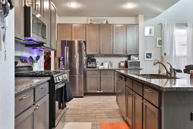 kitchen featuring backsplash, sink, dark brown cabinetry, light wood-type flooring, and stainless steel appliances