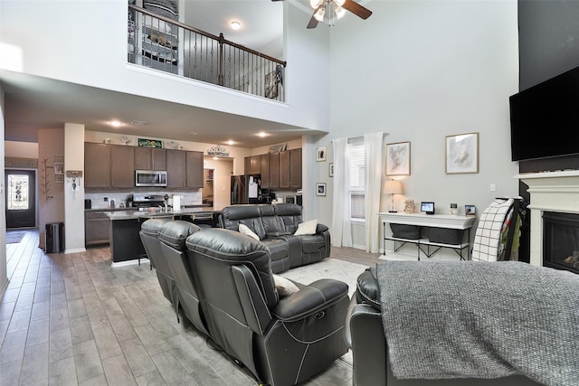 living room with ceiling fan, plenty of natural light, and a high ceiling