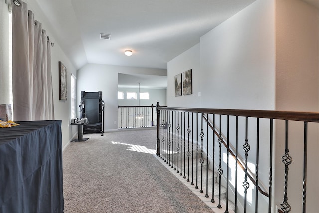 hallway with lofted ceiling and light colored carpet