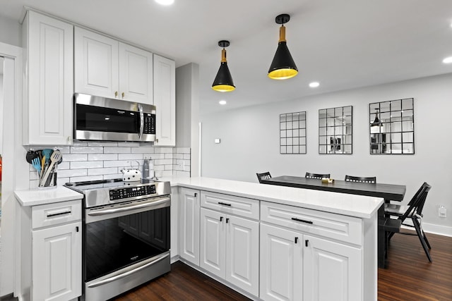 kitchen featuring appliances with stainless steel finishes, decorative light fixtures, dark wood-type flooring, white cabinetry, and kitchen peninsula