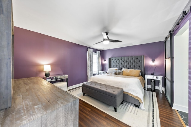 bedroom featuring dark wood-type flooring, ceiling fan, and a barn door