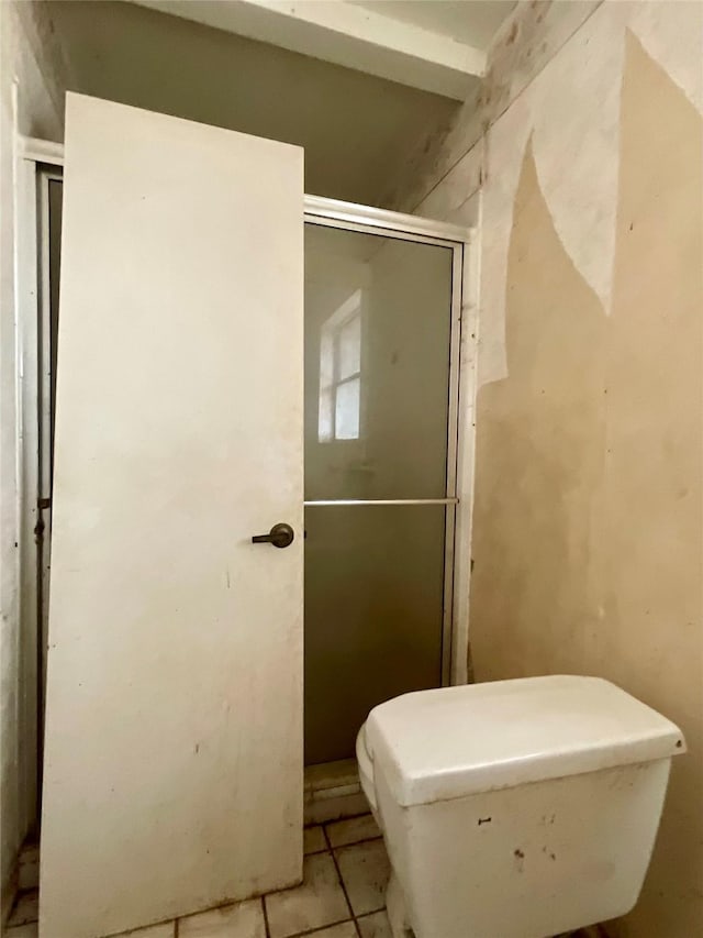 bathroom with toilet, tile patterned floors, and a shower with door