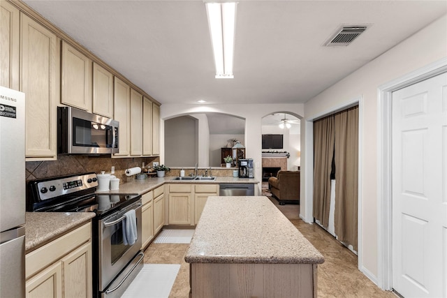 kitchen featuring light tile patterned floors, backsplash, stainless steel appliances, and a kitchen island