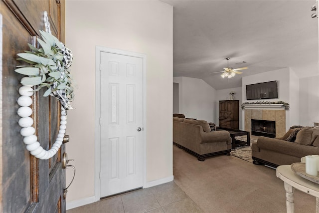 living room featuring ceiling fan, light tile patterned floors, lofted ceiling, and a tiled fireplace