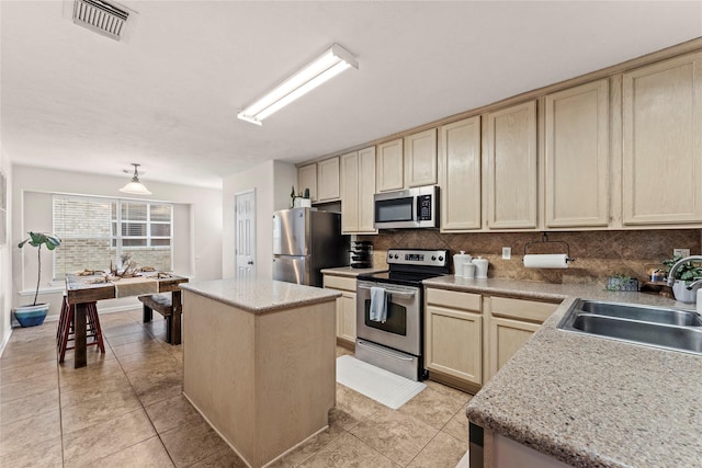 kitchen with appliances with stainless steel finishes, backsplash, light tile patterned flooring, a kitchen island, and sink