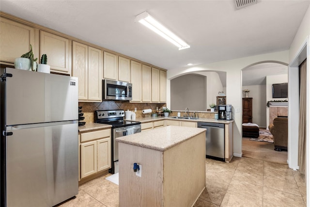 kitchen featuring backsplash, a center island, sink, stainless steel appliances, and light tile patterned floors