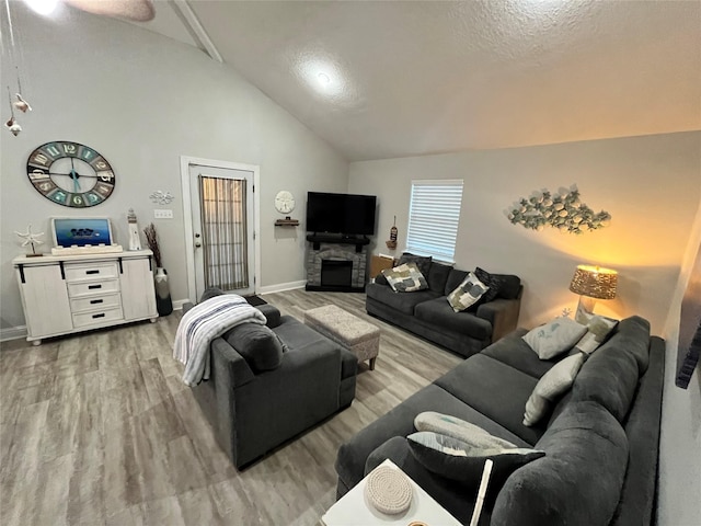 living area featuring a textured ceiling, high vaulted ceiling, a fireplace, wood finished floors, and baseboards