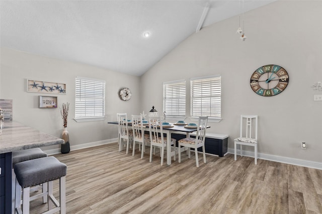 dining area featuring light wood-style floors, high vaulted ceiling, and baseboards