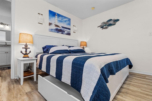 bedroom featuring a sink, baseboards, and wood finished floors