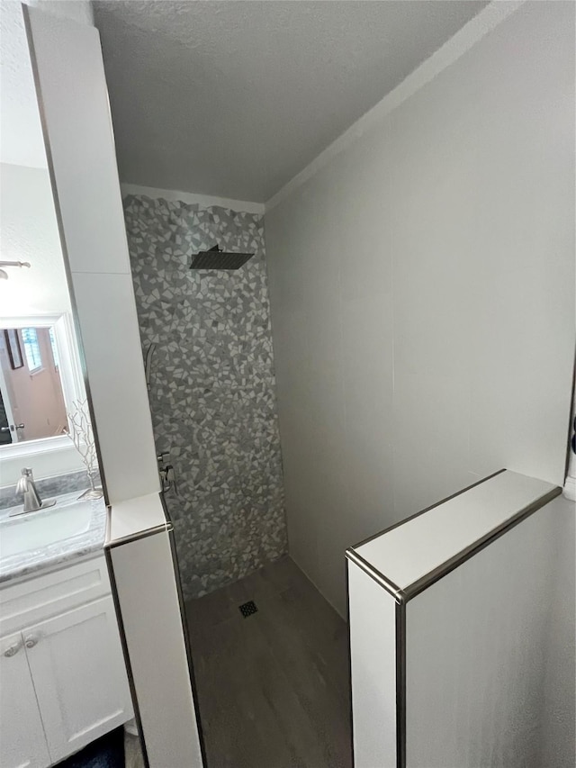 full bathroom with ornamental molding, a tile shower, and vanity