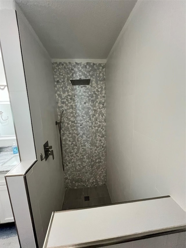 full bathroom featuring a tile shower and a textured ceiling