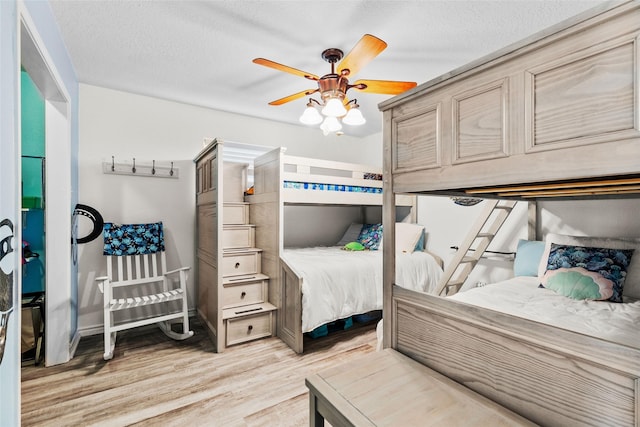 bedroom with light wood-type flooring, ceiling fan, and a textured ceiling