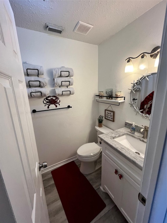 bathroom with visible vents, a textured ceiling, toilet, and wood finished floors