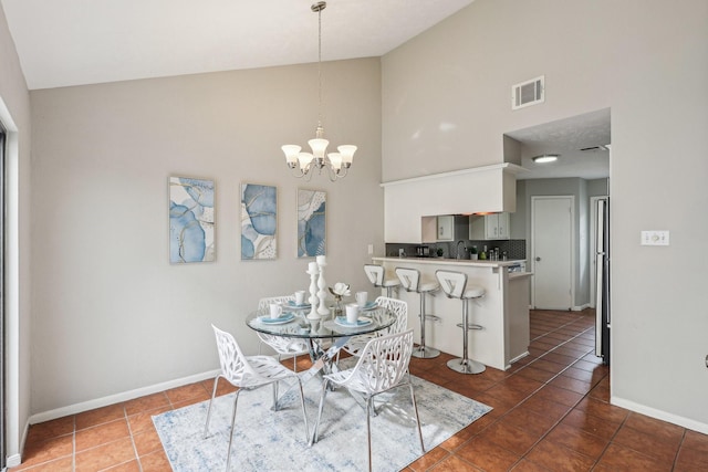 dining area with a chandelier, sink, dark tile patterned flooring, and high vaulted ceiling