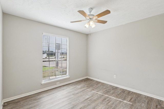 spare room with a textured ceiling, ceiling fan, a healthy amount of sunlight, and wood-type flooring