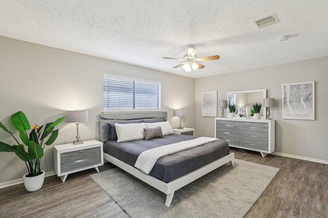 bedroom featuring ceiling fan, a textured ceiling, and dark hardwood / wood-style flooring