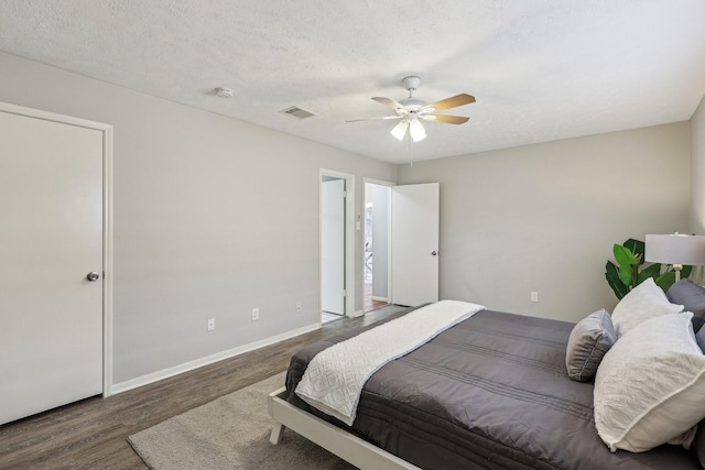 bedroom with ceiling fan, dark wood-type flooring, and a textured ceiling